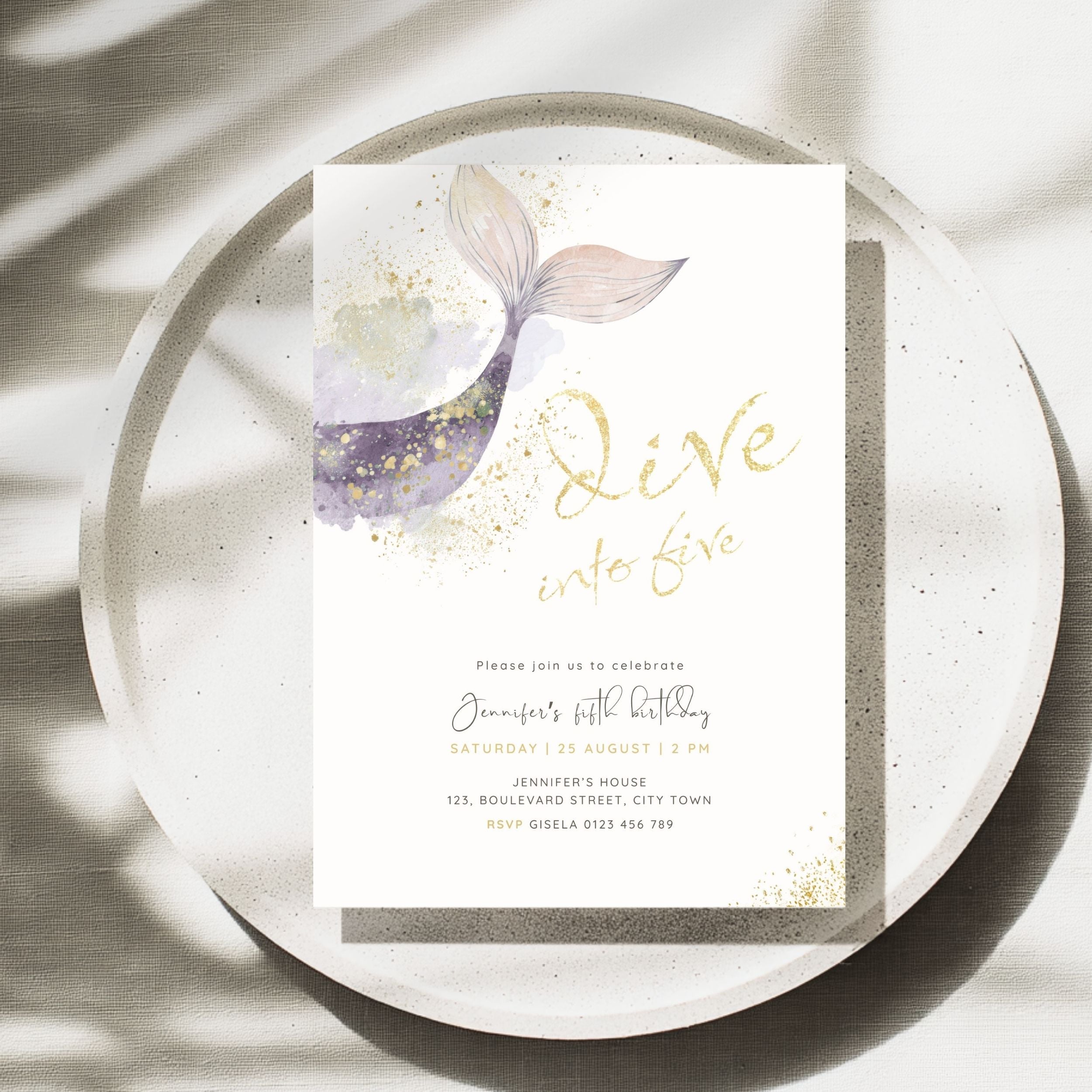 A square birthday invitation card featuring a watercolor mermaid tail design in purple, pink, and gold, with gold script text reading 'Dive into five' and black event details below, styled on a speckled white plate with soft leaf shadows.