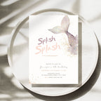 A mermaid-themed birthday invitation card displayed on a speckled white ceramic plate with soft leaf shadows. The card features a watercolor mermaid tail in lavender and purple, gold glitter accents, and the text 'Splash Splash' in a pink and mauve font.