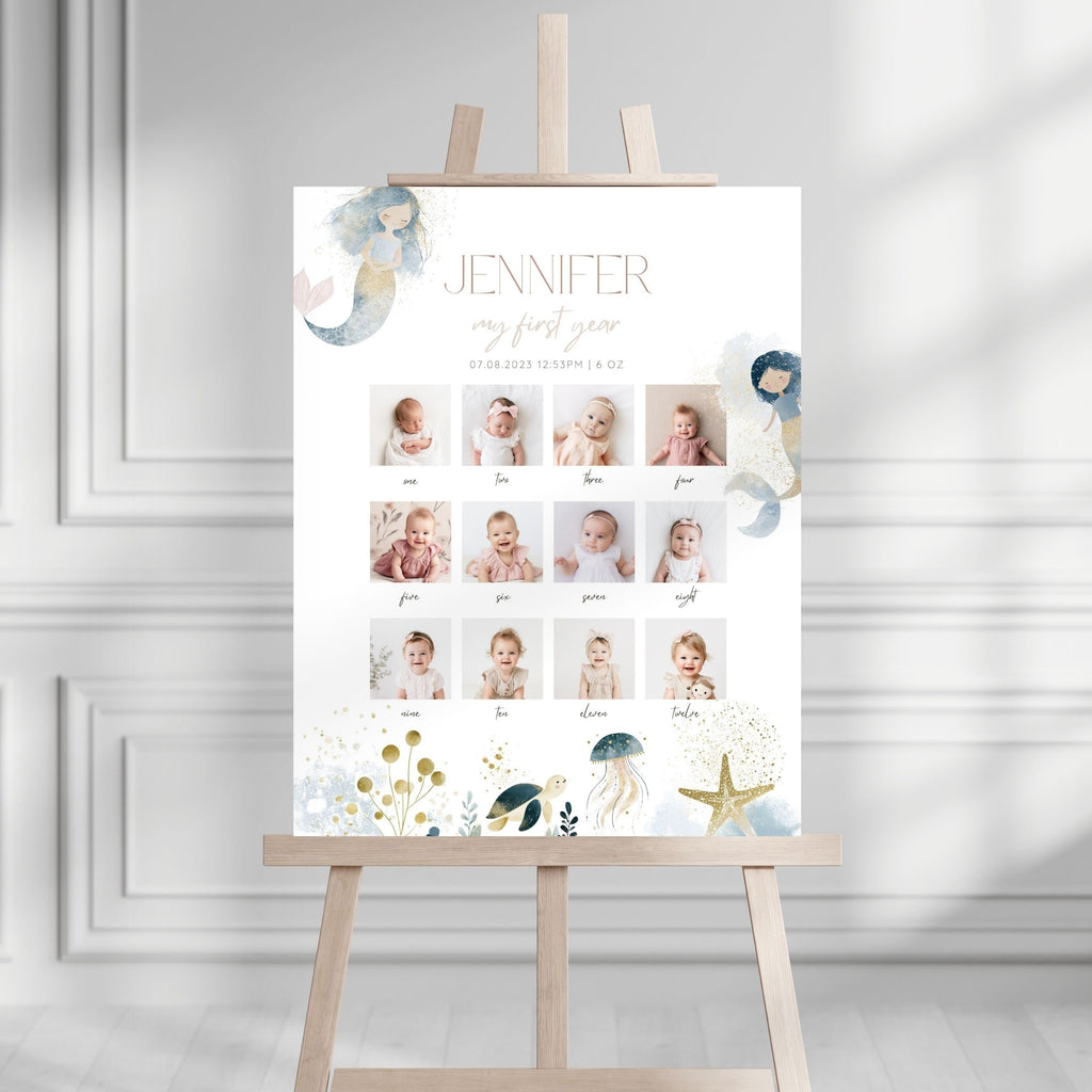 A personalized baby first-year photo timeline sign displayed on a wooden easel. The white sign features the name 'JENNIFER', 'my first year', and a grid of baby photos with labels.