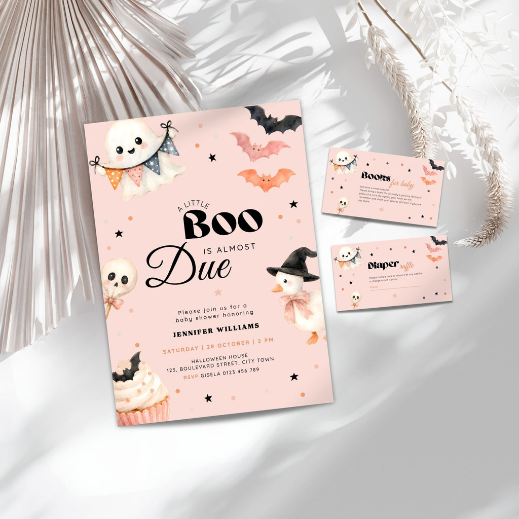 Pink halloween little boo baby shower invitation suite with a light blue card, matching RSVP card, and entrance card, decorated with cute cartoon ghosts, skulls, bats, and a witch, styled on a white surface with decorative dried palm leaves.