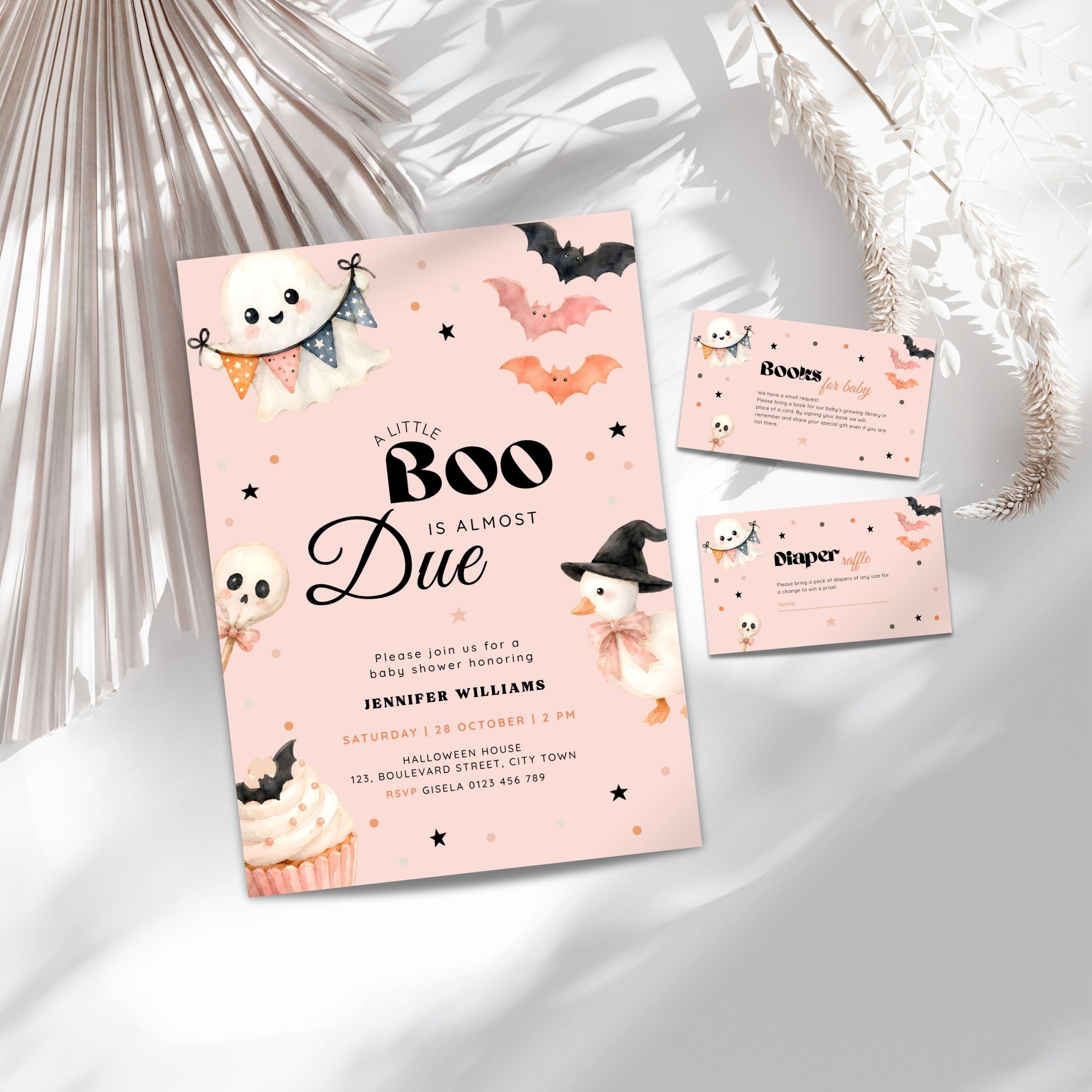 Pink halloween little boo baby shower invitation suite with a light blue card, matching RSVP card, and entrance card, decorated with cute cartoon ghosts, skulls, bats, and a witch, styled on a white surface with decorative dried palm leaves.