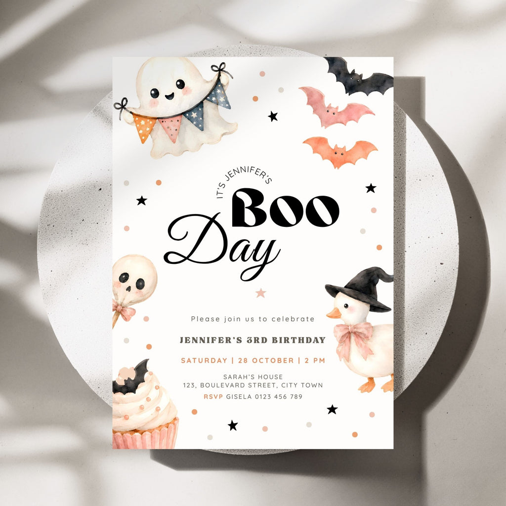 A Halloween-themed birthday invitation card for 'Boo Day' featuring cute watercolor illustrations of a ghost, bats, a skull lollipop, a cupcake, and a witch hat on a white background, styled on a round white plate with soft shadows.