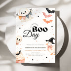 A Halloween-themed birthday invitation card for 'Boo Day' featuring cute watercolor illustrations of a ghost, bats, a skull lollipop, a cupcake, and a witch hat on a white background, styled on a round white plate with soft shadows.