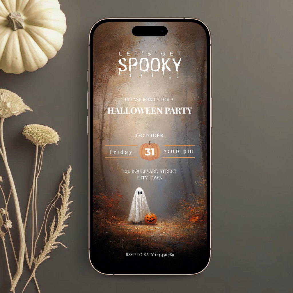 A smartphone centered on a dark gray surface, displaying a Halloween party invitation design with a ghost, pumpkin, and autumn forest scene. Decorative dried flowers and a small pumpkin sit to the left.