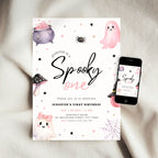 A Halloween-themed first birthday invitation card displayed on a soft beige fabric surface next to a smartphone showing the same design on screen. The card features cute watercolor illustrations of a ghost, cauldron, mushroom, spider, and web with the text 'Jennifer is a Spooky one' and event details.