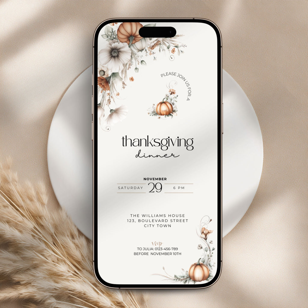 A smartphone mockup displays a Thanksgiving dinner invitation design with floral and pumpkin illustrations on a white background. The phone is centered on a round white plate with beige fabric and dried grass props.