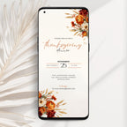A smartphone mockup displaying a Thanksgiving dinner invitation card with floral autumn illustrations in orange, rust, and cream on a white background, styled with dried palm leaves.