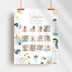 A vertical baby first-year photo collage poster with an ocean-themed design, hanging from two copper clips against a light gray wall. The white poster features gold and blue watercolor illustrations of a whale, octopus, jellyfish, starfish, and sea plants, along with twelve small photos of a baby named Sebastian and his family photos labeled with names and times.