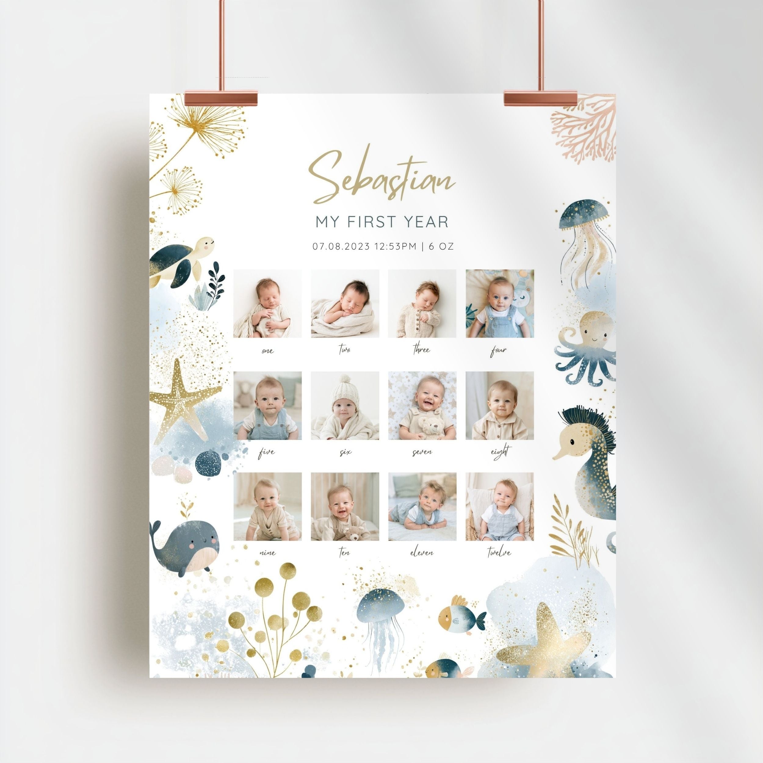 A vertical baby first-year photo collage poster with an ocean-themed design, hanging from two copper clips against a light gray wall. The white poster features gold and blue watercolor illustrations of a whale, octopus, jellyfish, starfish, and sea plants, along with twelve small photos of a baby named Sebastian and his family photos labeled with names and times.