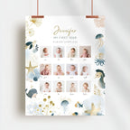 A personalized baby first year photo poster hanging from two copper clips against a white wall. The poster features a white background decorated with watercolor-style sea creatures like a whale, octopus, seahorse, and starfish in blue, gold, and beige.
