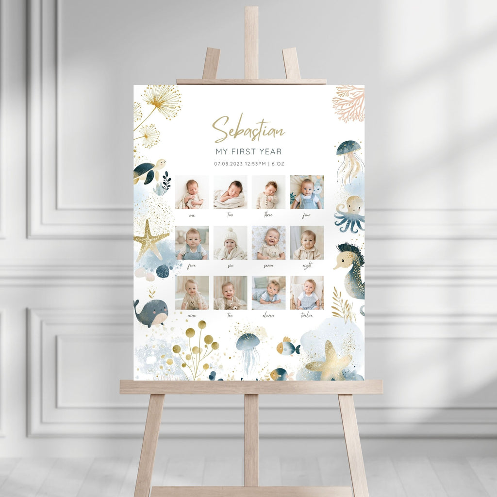 A personalized baby first-year photo wall display on a wooden easel, featuring a white background with gold and blue sea-themed illustrations and a grid of baby photos.